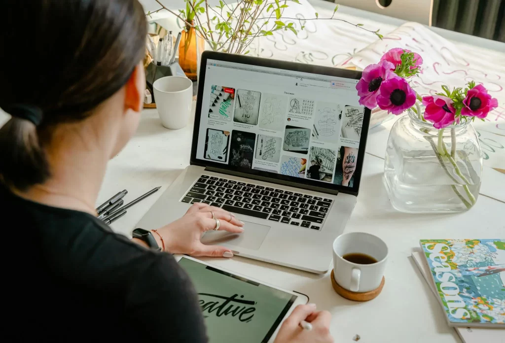 Graphic designer working at a laptop filled with creative sketches and mood boards, representing the innovative spirit of CDH WebDesign.