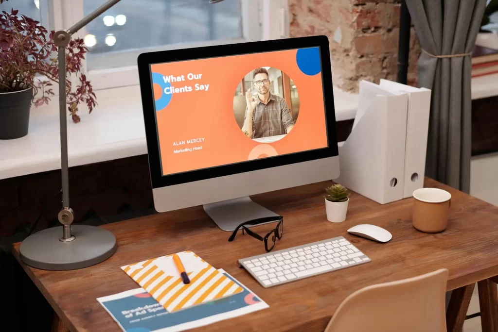 Modern workspace with an iMac displaying a client testimonial page, surrounded by design materials and a cozy office setup.